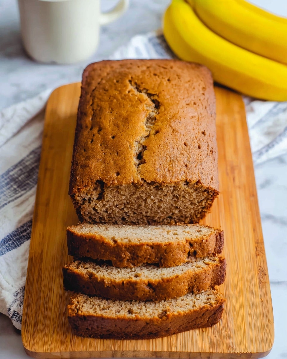 A sliced loaf of brown banana bread with a slightly rough texture is placed on a wooden cutting board. The bread has a golden brown crust with small cracks on the surface. To the upper right side, there are two whole yellow bananas resting on a white cloth with a blue striped edge. In the top left corner, part of a white mug can be seen, all set on a white marbled surface. photo taken with an iphone --ar 4:5 --v 7