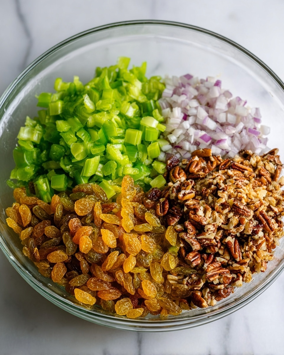 A clear glass bowl holds four distinct layers of ingredients neatly arranged side by side. On the left side, there is a pile of bright green chopped celery pieces with a crisp texture. Next to the celery, finely chopped light purple shallots create a soft, delicate layer. To the right of the shallots, there is a heap of finely chopped brown pecans mixed with a few golden raisins, giving a rough, crunchy texture with small yellow-brown spots. The final section, at the bottom left, is a large pile of shiny golden raisins with a smooth, wrinkled surface. The bowl is placed on a white marbled texture surface. photo taken with an iphone --ar 4:5 --v 7