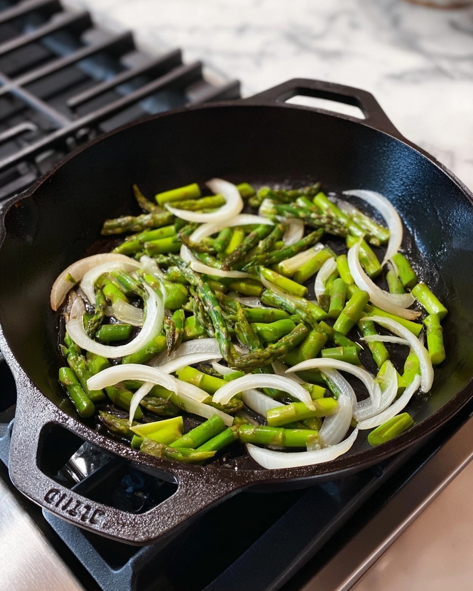 A black cast iron pan on a stove contains a simple stir-fry of green asparagus pieces and translucent white onion slices. The asparagus is cut into small sections, showing bright green with some cooked edges, and is mixed evenly with curved white onion slices. The pan's surface has a slight shine from cooking oil. The background shows parts of the stove with clean grates and a white marbled texture nearby. photo taken with an iphone --ar 4:5 --v 7