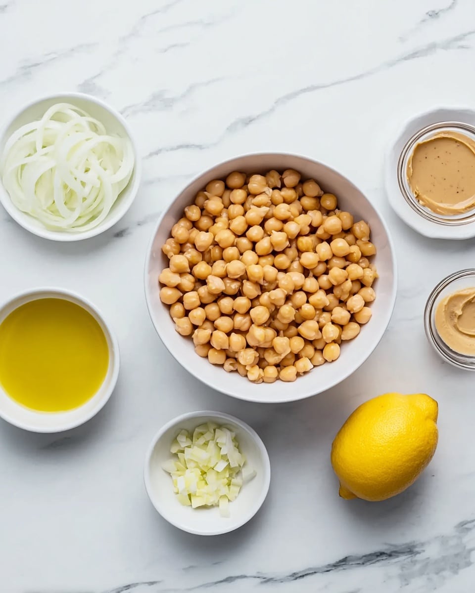 A white bowl filled with a large layer of light golden chickpeas sits at the center on a white marbled surface. Around it, there are five small white bowls, each holding different ingredients: one with bright yellow olive oil, one with light beige tahini sauce, one with thin slices of white onion, one with a small amount of chopped pale yellow garlic, and nearby is a whole bright yellow lemon. The arrangement is neat and spaced out, with all items placed on the white marbled texture. photo taken with an iphone --ar 4:5 --v 7