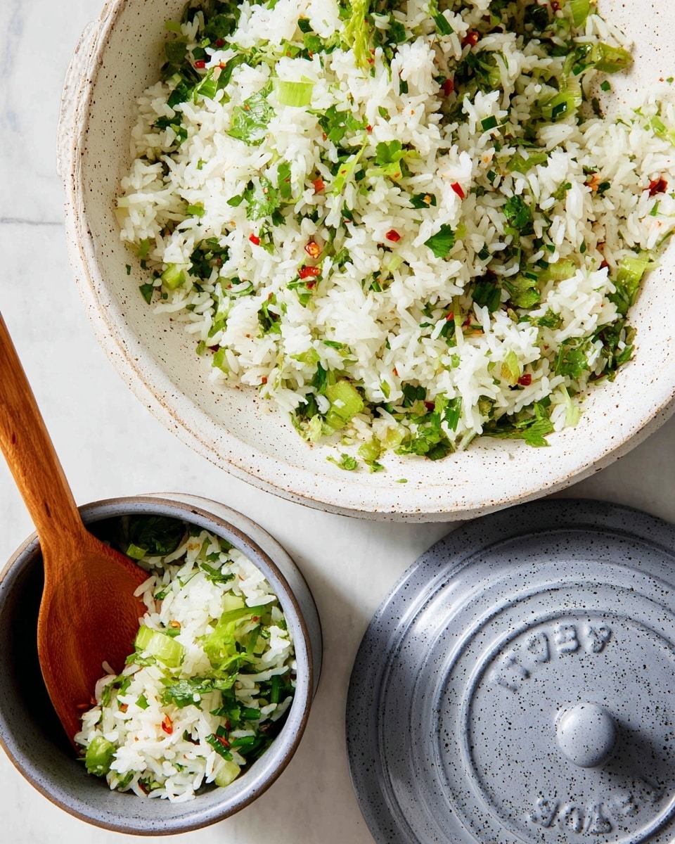The image shows a close-up of cooked white rice mixed with green herbs and chopped green onions, served in two containers: one is a round white speckled plate filled with a generous layer of the rice mixture, and the other is a grey small pot with a wooden spoon resting inside the rice; the pot’s lid sits next to it on a white marbled surface. The rice grains are fluffy and bright white, interspersed with vibrant green herbs and small bits of red chili flakes, adding color contrast. The textures of the rice and herbs look fresh and light. Photo taken with an iphone --ar 4:5 --v 7