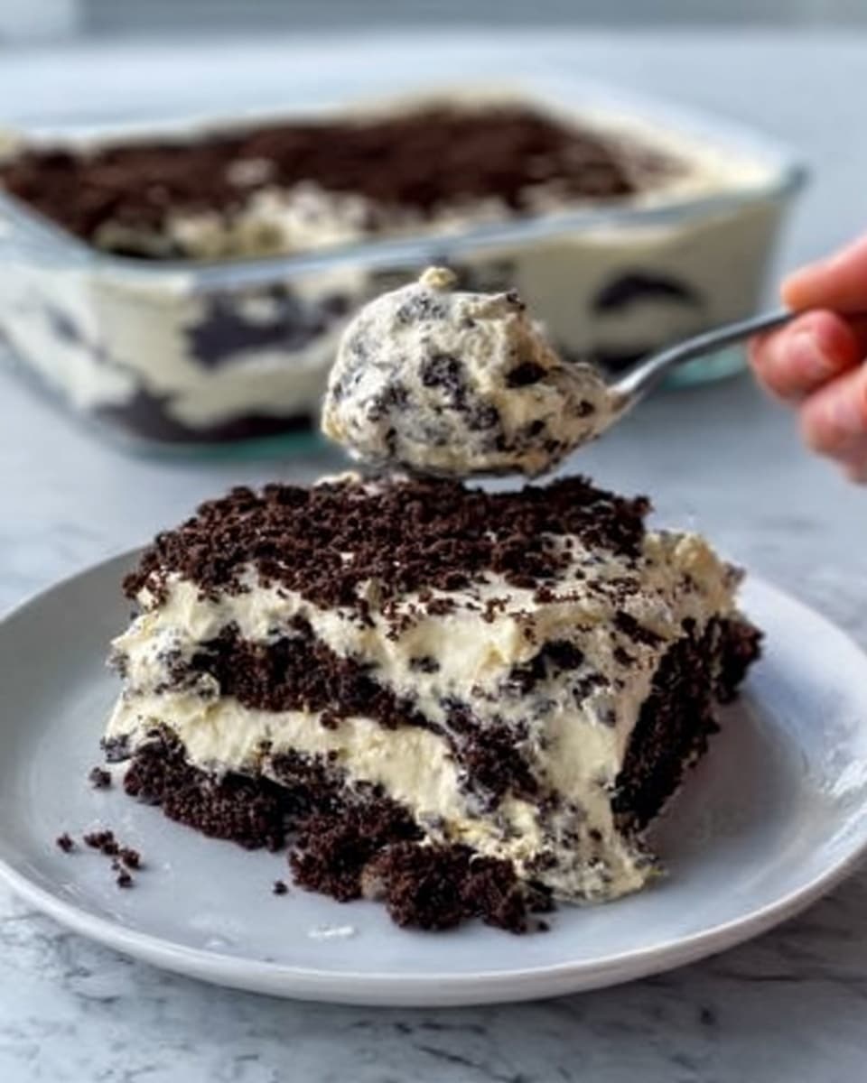 The image shows a white plate with a large scoop of a layered dessert. The dessert has two main layers: the bottom layer is a thick, dark brown crumbly chocolate layer with a rough texture, and on top is a creamy white layer with dark chocolate chips mixed in, giving it a speckled look. The creamy layer looks soft and smooth. In the background, there is a clear white dish filled with the same dessert, showing the dark chocolate base and the creamy white topping. The setting is on a white marbled surface. A spoon is placed on the plate, with a woman's hand holding it to scoop the dessert. photo taken with an iphone --ar 4:5 --v 7