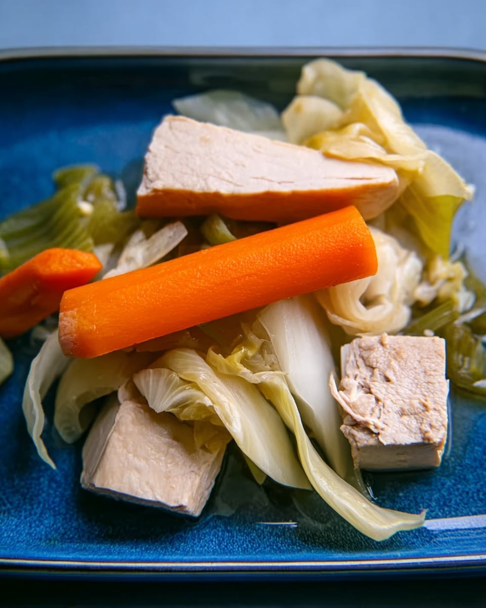 The image shows a blue rectangular plate with a simple arrangement of cooked vegetables and pieces of meat. There are three main layers: a bright orange carrot stick in the middle, thick pieces of pale beige meat on either side, and a mix of light green celery stalks and pale cabbage leaves layered around and over the carrot and meat. The textures appear soft and slightly wet, with the vegetables and meat placed loosely next to each other on the plate. The background is not visible, but the plate takes most of the focus. Photo taken with an iphone --ar 4:5 --v 7