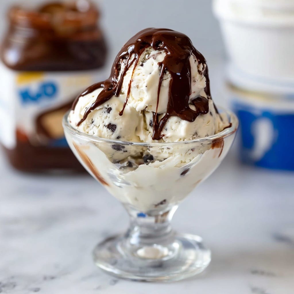 A small jar filled with thick, shiny dark chocolate sauce that is smooth and glossy, with the sauce overflowing and dripping down the sides of the jar in thick ribbons. The jar shows a slight embossed design on its surface, and in the blurry background, two white tubs with blue lids are visible on a white marbled surface, adding contrast to the rich chocolate color. Photo taken with an iphone --ar 4:5 --v 7