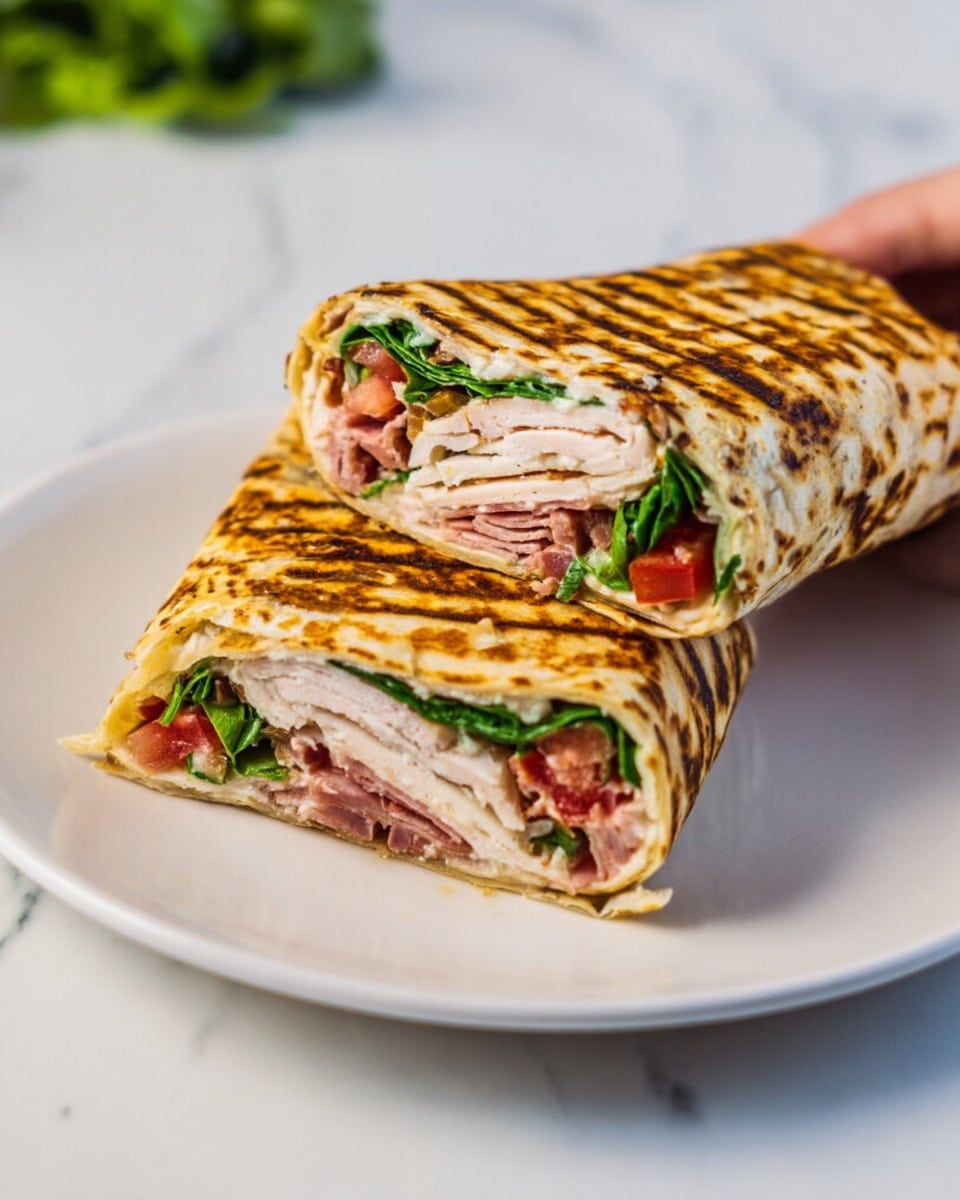 Two grilled wraps cut in half are placed on a white plate on a white marbled surface. Each wrap has a golden brown, slightly charred texture with visible grill marks. Inside, the wraps have three main layers: a layer of sliced light pink turkey or chicken, a layer of thin dark pink slices of ham, and a layer of bright green spinach leaves topped with small pieces of diced red tomatoes, all held inside the wrap. A woman's hand holds one half of a wrap at the top of the image. photo taken with an iphone --ar 4:5 --v 7