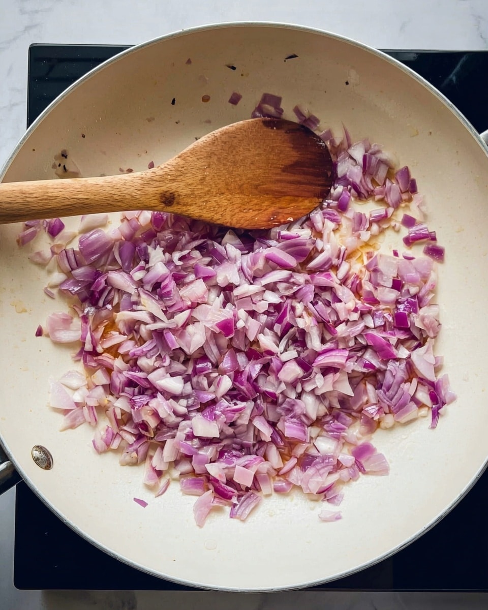 A white pan filled with small chopped red onions that show layers of purple and white colors, with some pieces lightly cooked to a translucent light purple. A wooden spoon is resting in the pan, stirring the onions. The pan sits on a black cooktop against a white marbled surface background. photo taken with an iphone --ar 4:5 --v 7