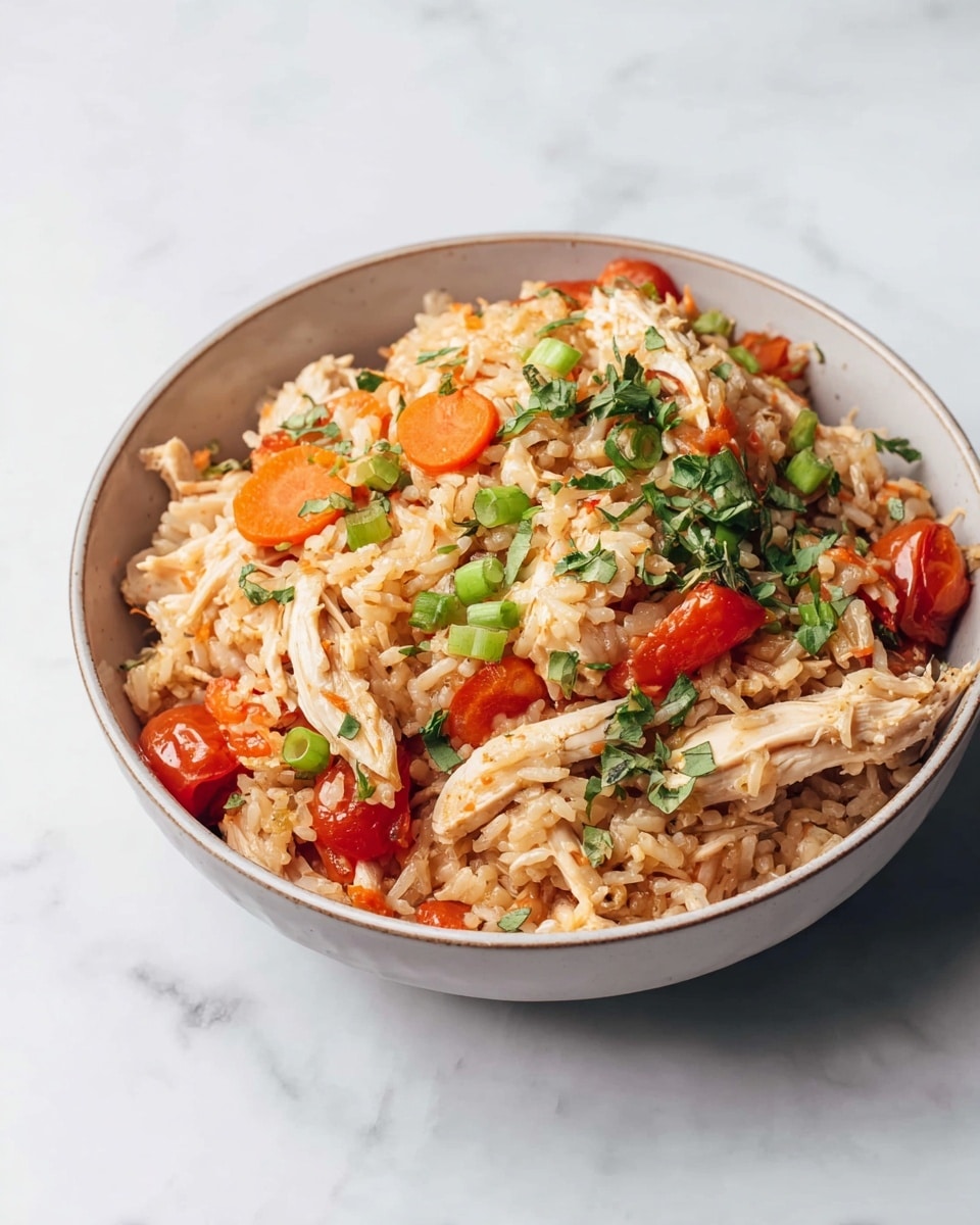 A close-up of a white bowl filled with cooked rice mixed with shredded light brown chicken pieces, orange carrot slices, and small diced red tomatoes. The rice is fluffy and pale beige, mixed with green chopped herbs and scallions sprinkled on top. A spoon holding a scoop of this mixture, with chicken and a carrot piece, is shown lifting from the bowl. The background is a white marbled texture. Photo taken with an iphone --ar 4:5 --v 7