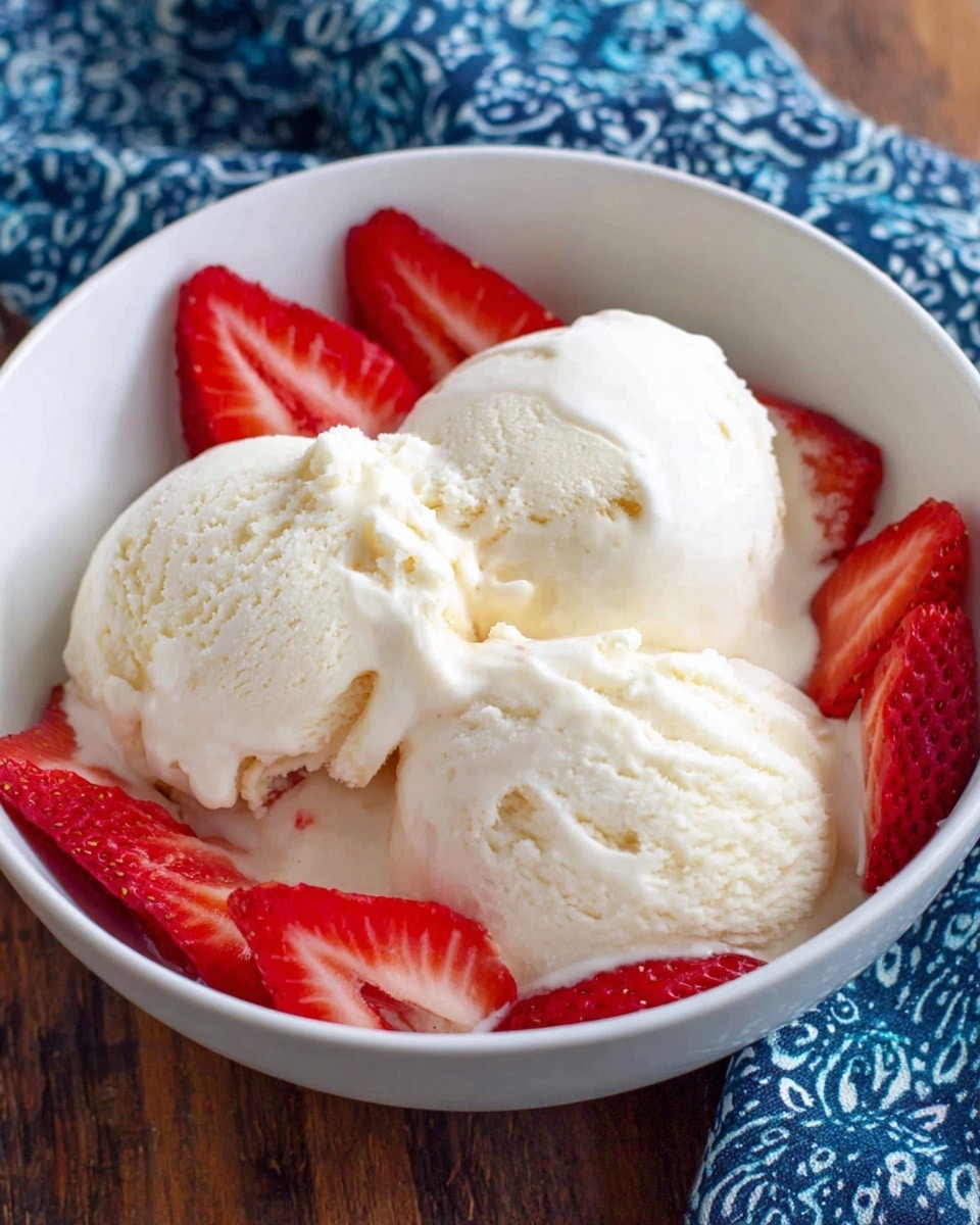 A white bowl filled with three scoops of creamy vanilla ice cream showing a smooth and slightly melting texture, surrounded by slices of bright red strawberries placed evenly around the edge of the bowl. The bowl sits on a wooden surface with a blue patterned cloth in the background. photo taken with an iphone --ar 4:5 --v 7