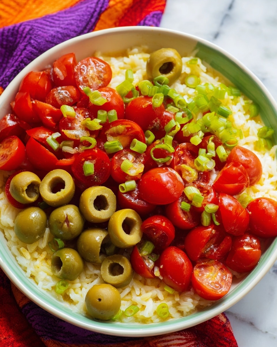 A close-up view of a white bowl filled with three main layers: the bottom layer is yellowish cooked rice, the middle layer is a mix of halved red cherry tomatoes and sliced green olives, and the top layer is small green onion pieces sprinkled over the olives and tomatoes. The bowl sits on a white marbled surface with part of a colorful cloth in red, orange, and purple shades visible in the background. photo taken with an iphone --ar 4:5 --v 7