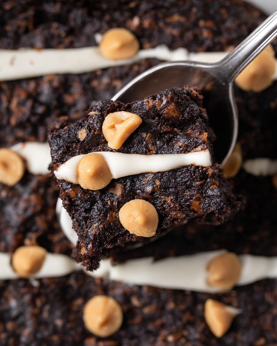 A close-up of a dark chocolate brownie square being lifted by a silver spoon. The brownie has a rough, moist texture with visible small chunks inside. On top of the brownie are several light brown peanut butter chips scattered around and a thick white creamy line running across the brownie and the larger brownie base beneath it. The bigger brownie layer also shows the same uneven texture with embedded peanut butter chips and white creamy lines placed in rows. The background surface is a white marbled texture. Photo taken with an iphone --ar 4:5 --v 7