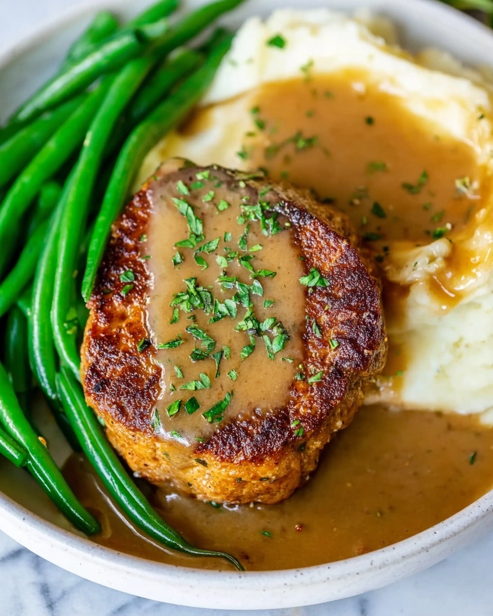 A white plate holds three main layers: on the left side, bright green cooked green beans with a smooth texture, in the middle sits a thick, round, browned patty topped with finely chopped green herbs, and on the right, a creamy layer of mashed potatoes partially covered with light brown gravy that spills over the patty and the plate, all set on a white marbled surface; the image is close-up, showing detailed textures and colors, photo taken with an iphone --ar 4:5 --v 7