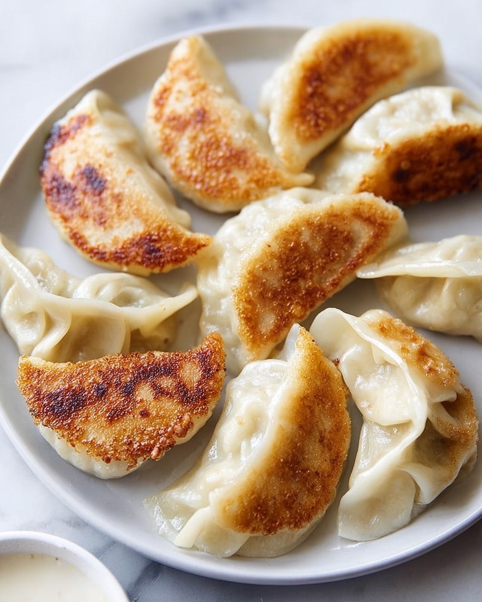 The image shows a white plate filled with pan-fried dumplings arranged in a circle. The dumplings have a crescent shape with pleated edges. Some of them are golden brown and crispy on one side, while others are soft and steamed with a smooth, light beige color. The plate sits on a white marbled surface, and a small part of a white bowl with dipping sauce is visible at the edge. The photo emphasizes the contrast between the golden, crispy texture and the soft, steamed dough of the dumplings. photo taken with an iphone --ar 4:5 --v 7