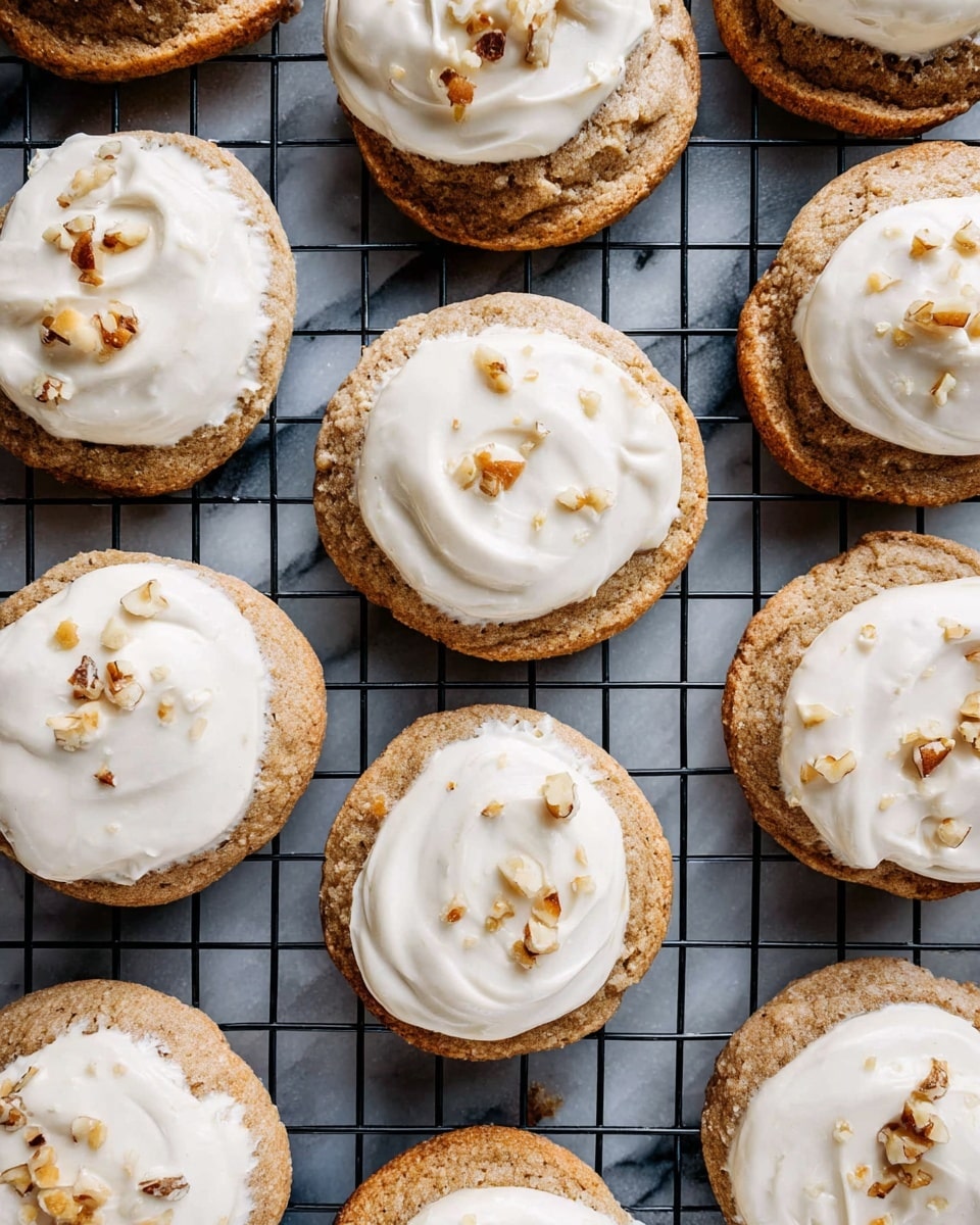 The image shows many round cookies arranged closely on a black cooling rack with a white marbled surface underneath. Each cookie has one thick layer of light brown dough with a slightly rough texture, topped with a thick, smooth layer of white frosting spread unevenly in a circular motion. Small pieces of chopped nuts are scattered on top of the frosting, adding texture and a golden brown color contrast. The cookies are placed in an organized grid pattern, filling the entire frame. photo taken with an iphone --ar 4:5 --v 7