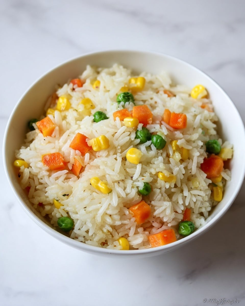 The image shows a white electric rice cooker filled with cooked white rice mixed with small pieces of bright orange carrot, yellow corn kernels, and green peas evenly distributed throughout the top layer of rice. The rice grains appear fluffy and separate with the colorful vegetables adding texture and color contrast. The inside rim of the cooker is silver metal, reflecting some light. The cooker is set against a white marbled surface, and no other items are visible. photo taken with an iphone --ar 4:5 --v 7