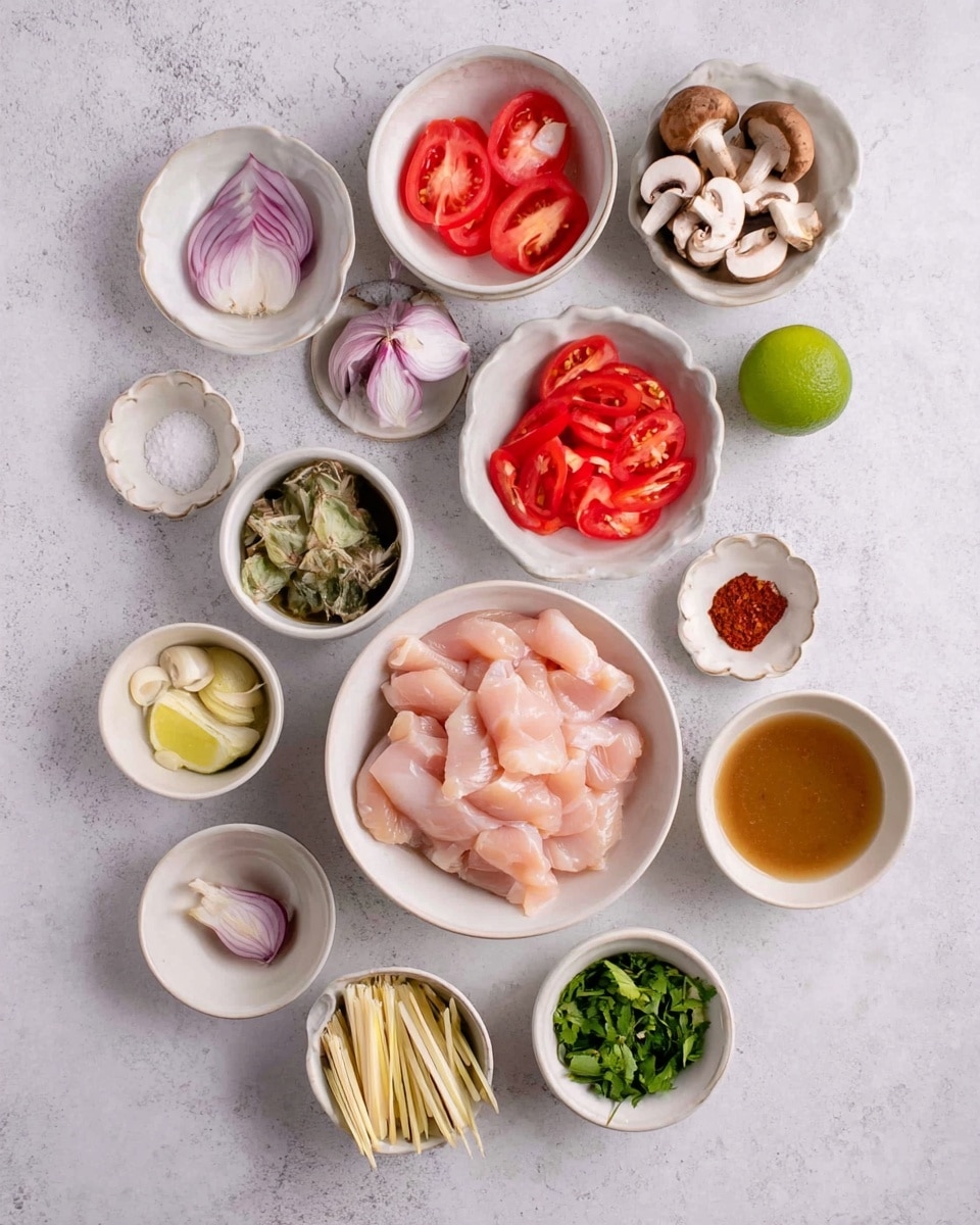 The image shows several white bowls and small white plates arranged on a white marbled surface, each holding different raw ingredients. At the center is a white bowl filled with light pink raw chicken slices. Surrounding it are smaller white bowls containing sliced red tomatoes, chopped green herbs, thin red pepper strips, sliced mushrooms, sliced shallots, and sliced ginger. There are also a few small white plates with salt, ground black pepper, and a red paste. A whole green lime sits near the top middle. One bowl holds pale yellow lemongrass stalks, and another scalloped bowl contains a light brown liquid, likely a sauce or broth. photo taken with an iphone --ar 4:5 --v 7