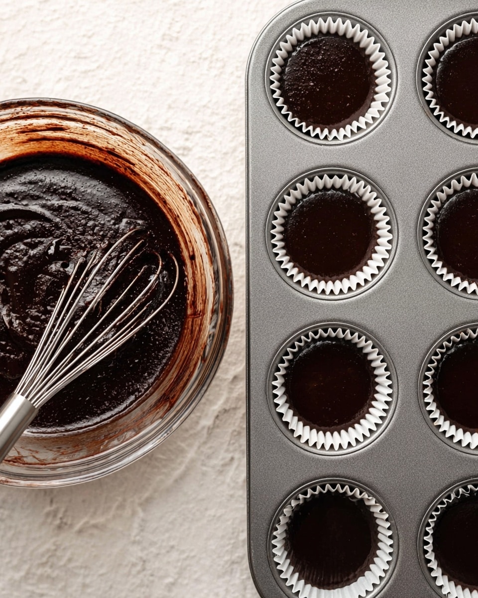 The image shows two pictures side by side on a white marbled surface. The left picture is a close-up of a clear glass bowl filled with dark chocolate batter with a smooth and slightly shiny texture. In the batter, there is a metal whisk partially dipped, coated with the thick dark batter. The bowl edges have some batter smudges. The right picture shows a grey metal muffin tray with nine cavities, each lined with white paper cupcake liners filled evenly with the same dark chocolate batter. The batter in each liner is smooth and shiny, set to bake. photo taken with an iphone --ar 4:5 --v 7